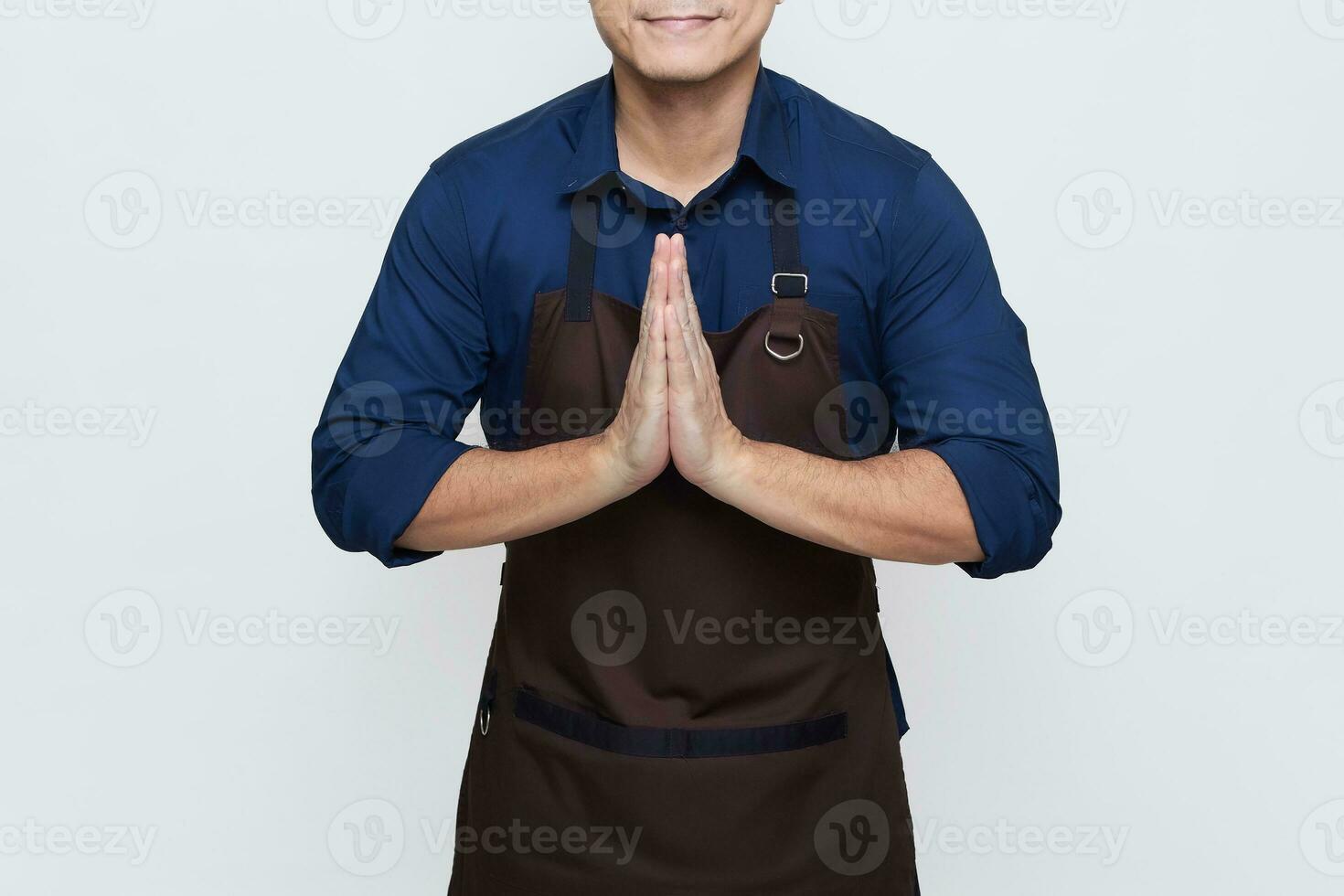 Asian Man wearing Apron in casual stylish clothing, standing tall pose with both hands clasped together, showing hospitality, no face isolated white background photo
