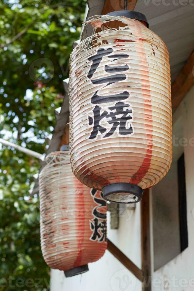 antiguo y Rasgado tradicional japonés tienda firmar linterna, colgado en frente de el Tienda foto