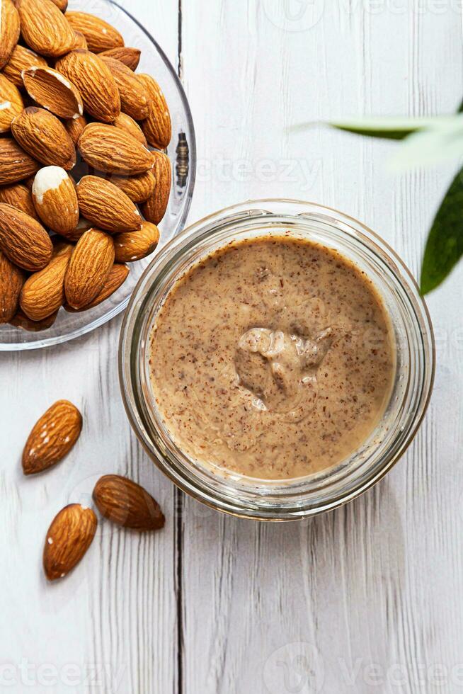 Jar of almond butter with almonds heap. Homemade almond butter, natural, healthy food. photo