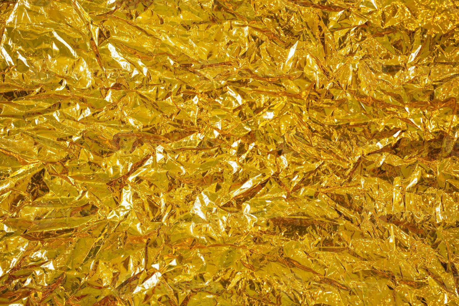 Gold foil abstract wrinkled texture, close up. photo