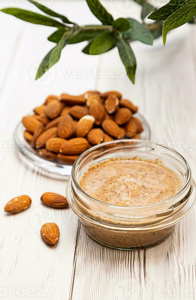 Jar of almond butter with almonds heap. Homemade almond butter, natural, healthy food. photo