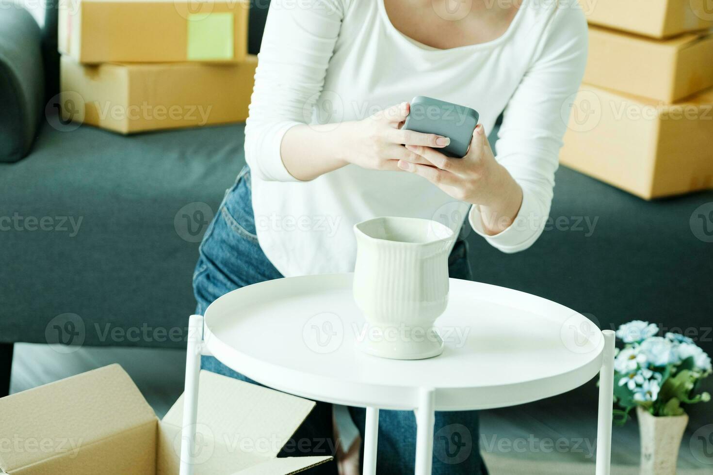 Young asian business owner holding phone and retail package parcel. photo