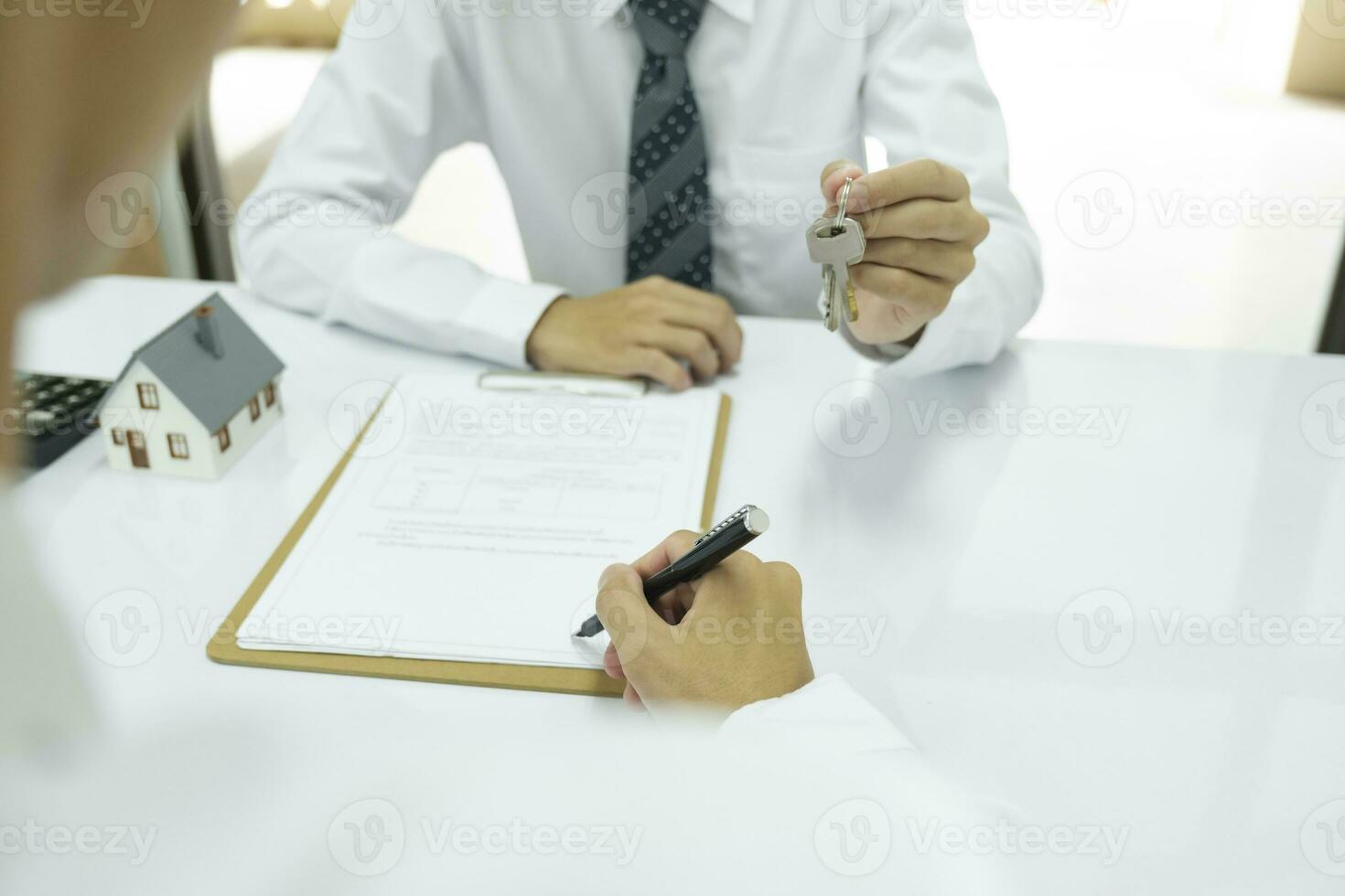Real estate agent giving house keys to client after signing home loan contract. photo