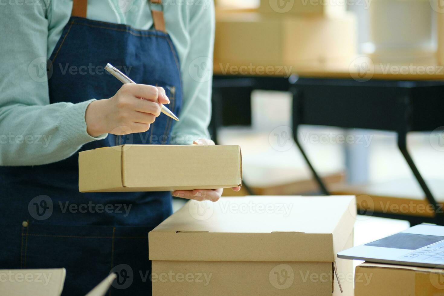 Online small business owner writing address on parcel box. photo