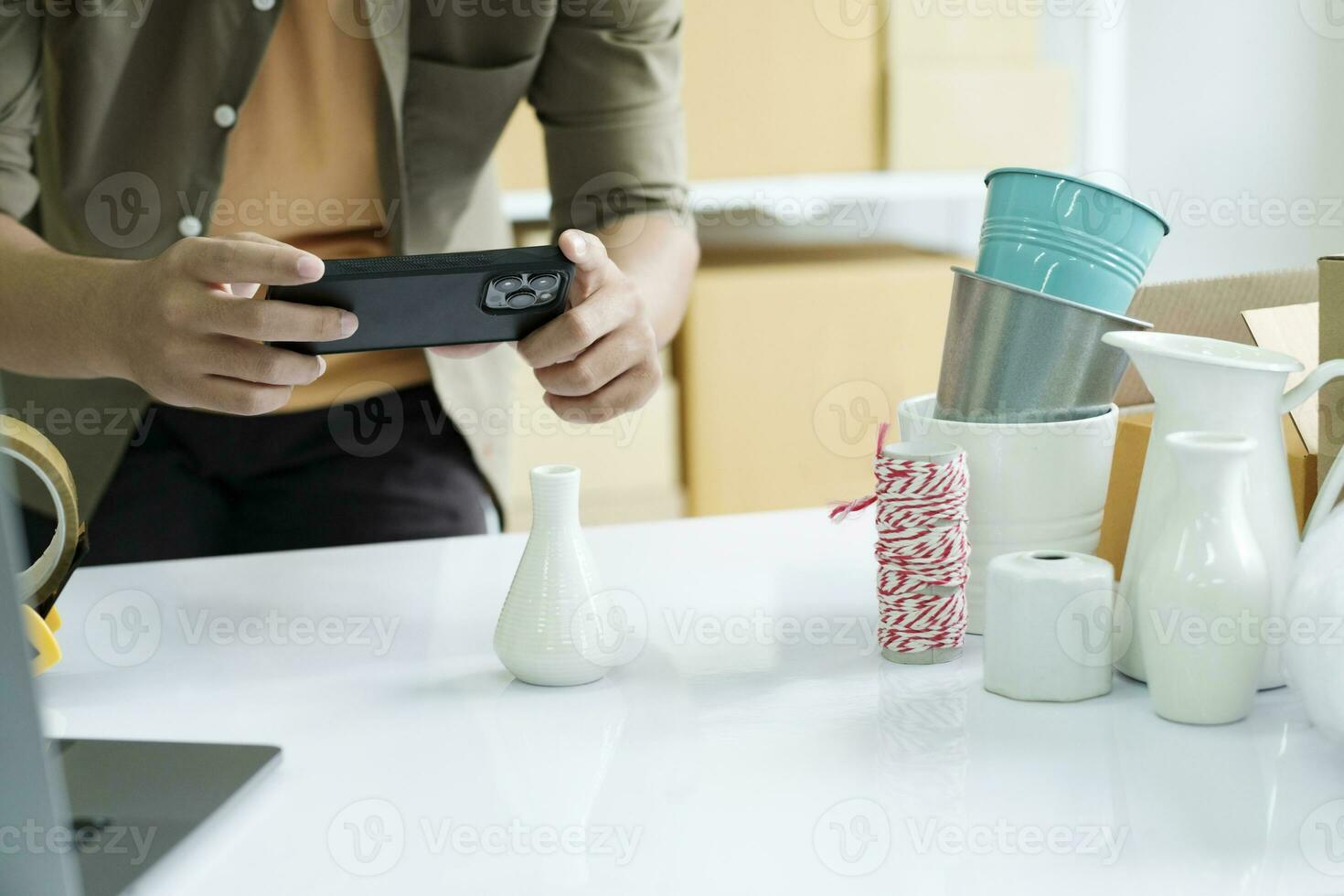 Young male online business owner using cellphone checking parcel box. photo