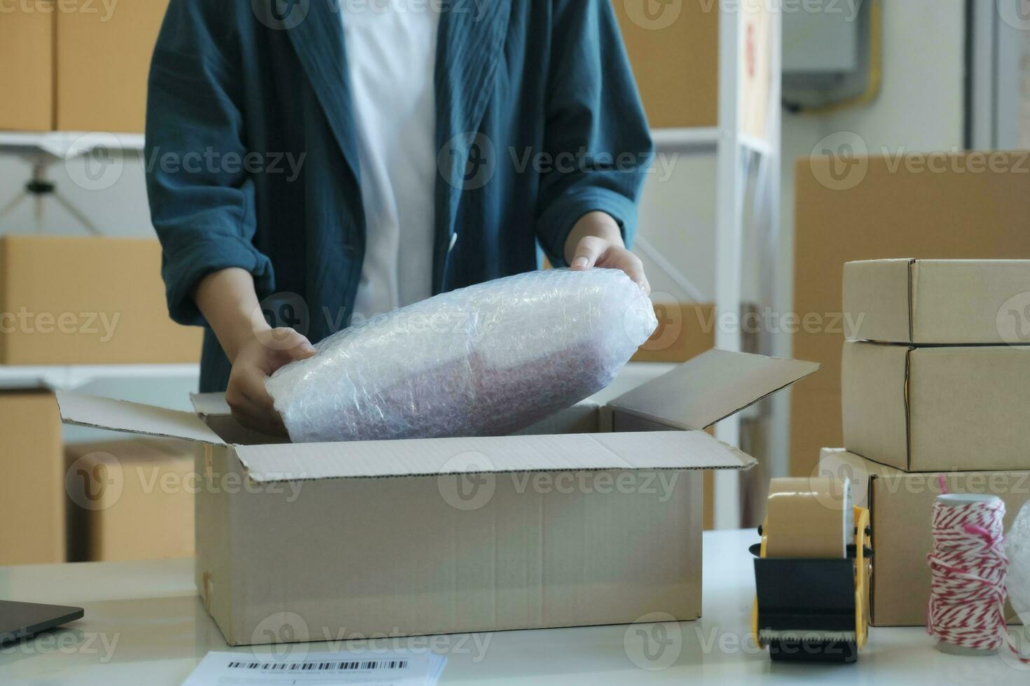 Young entrepreneur packing product in mailing box for shipping. photo