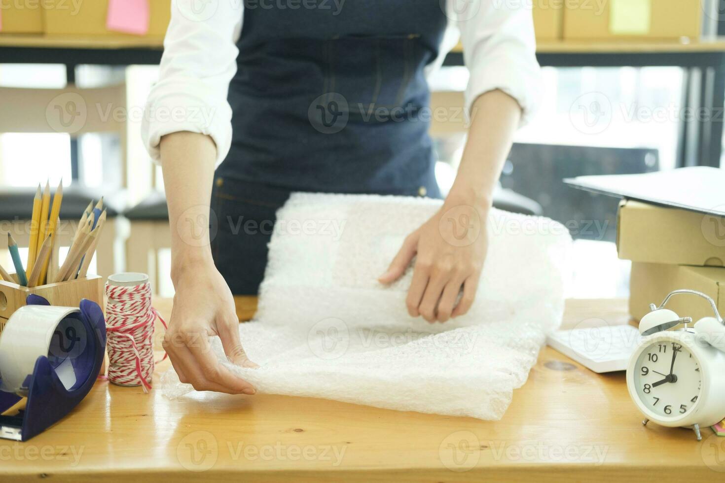 Asian female clothes shop owner folding a t-shirt and packing in a cardboard parcel box. photo