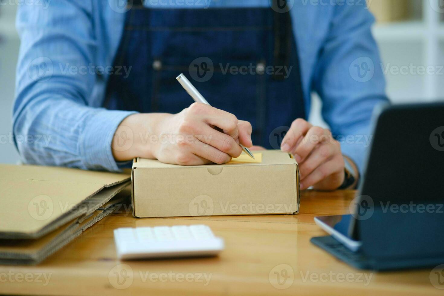 Start up small business owner writing address on cardboard box a. photo