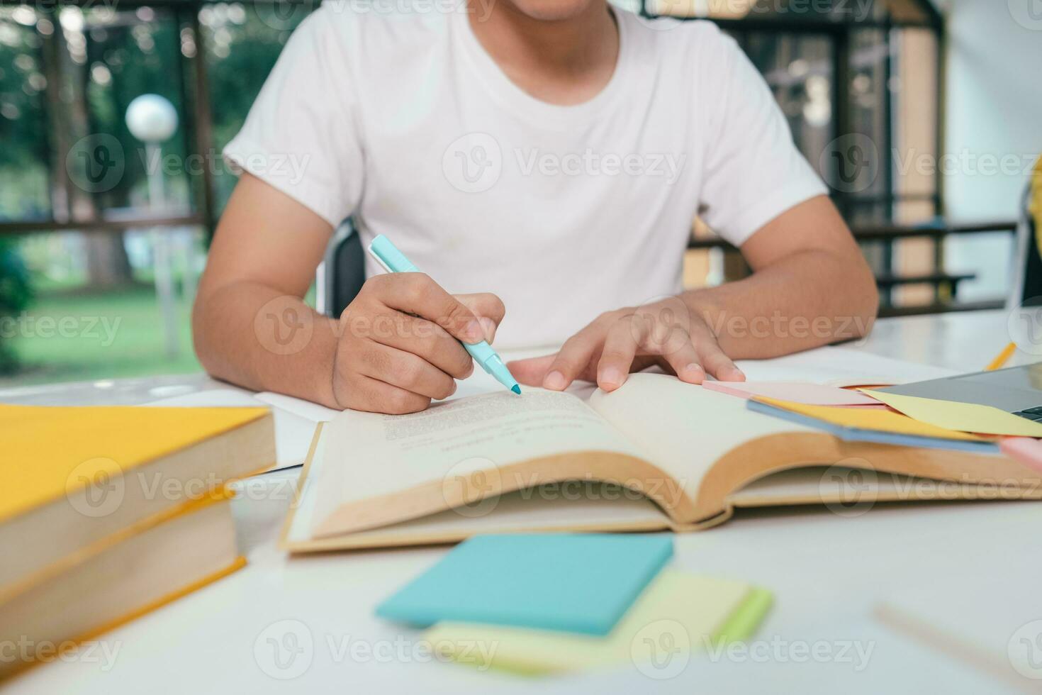 Close up young Asian male student is preparing to reading a books for exams at university. photo