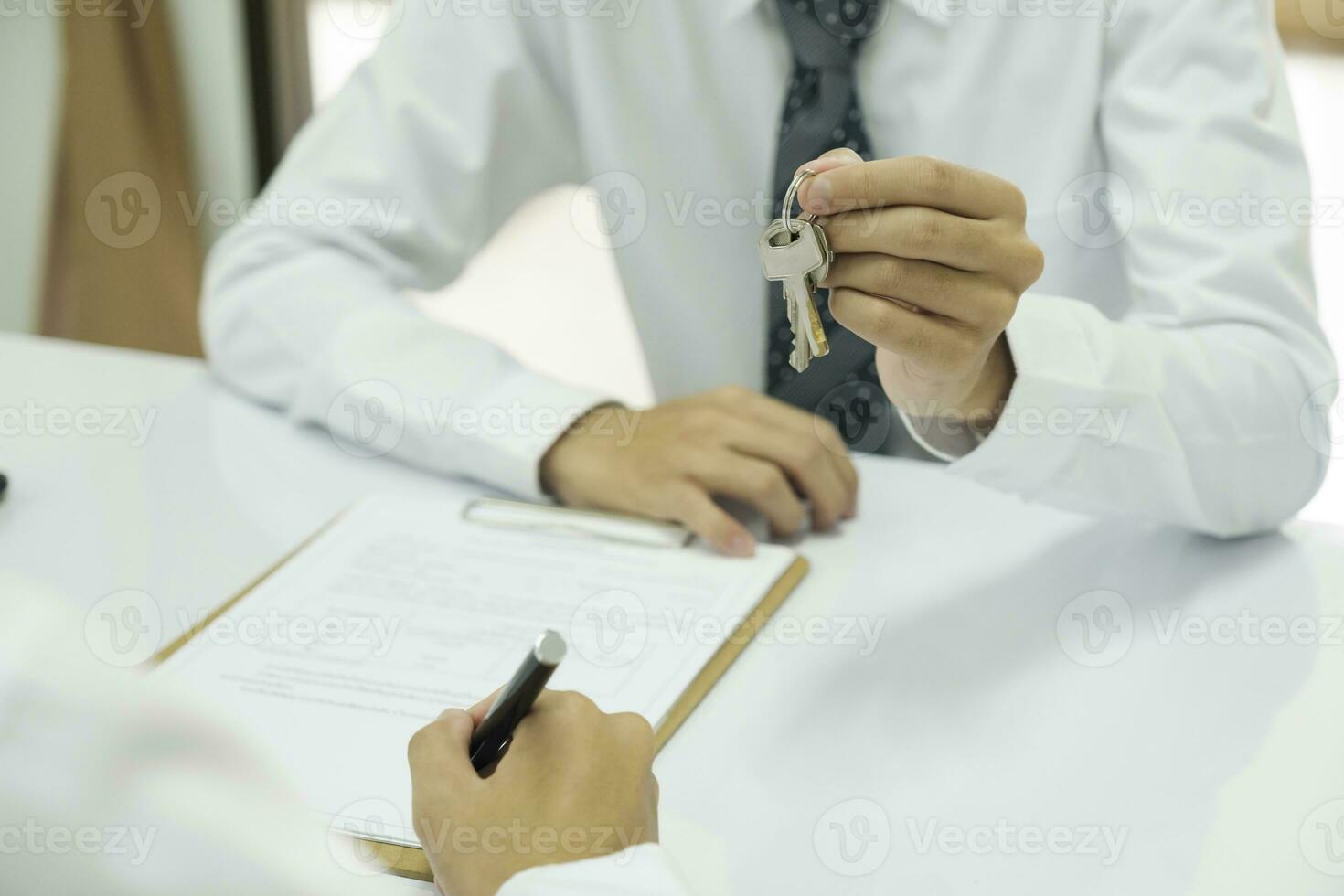 Real estate agent giving house keys to client after signing home loan contract. photo