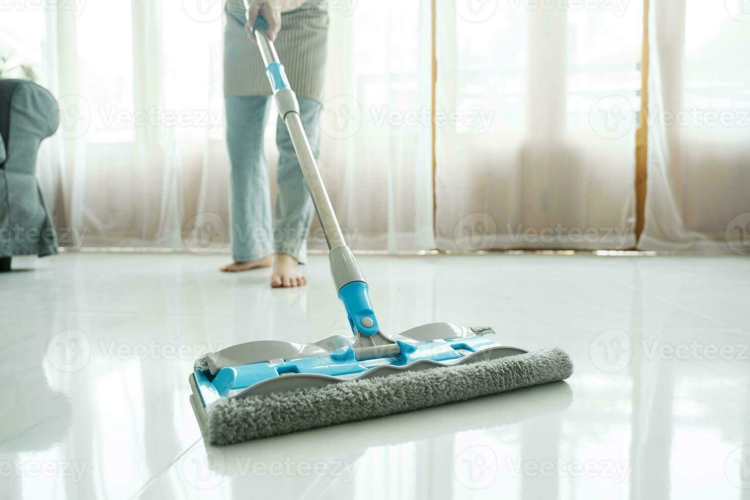 Young woman cleaning floor using mop at home. photo