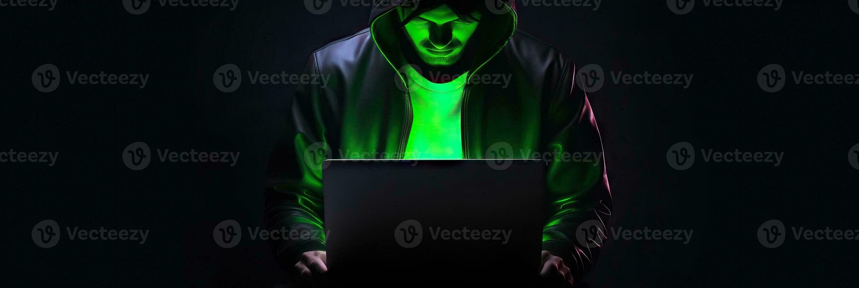 Hacker without face in a hood holds a laptop. on a dark background. Banner for cyber security.  Internet web hack technology. Digital laptop in hacker man hand isolated on black. photo