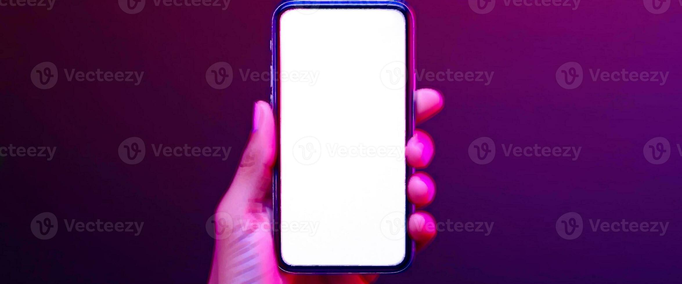 Phone in hand. Silhouette of male hand holding bezel-less smartphone with futuristic neon light on dark background. Screen is cut with clipping path. photo