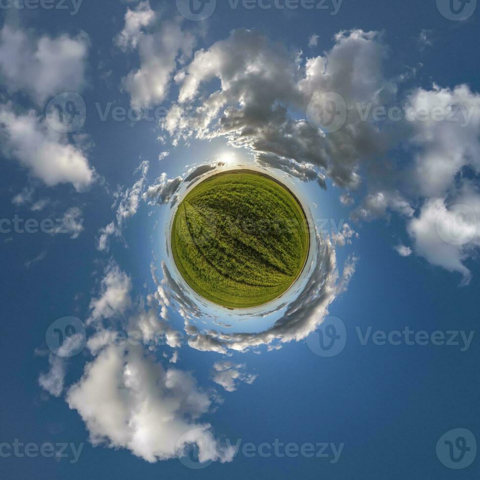 green tiny planet in blue sky with beautiful clouds with transformation of spherical panorama 360 degrees. Curvature of space. photo