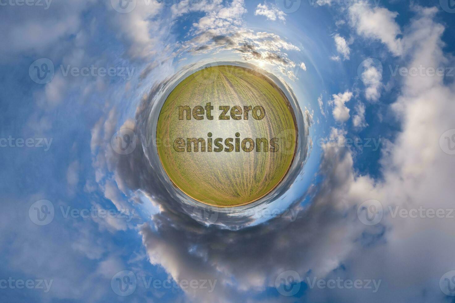 net zero emissions text concept image against green tiny planet in blue sky with beautiful clouds photo