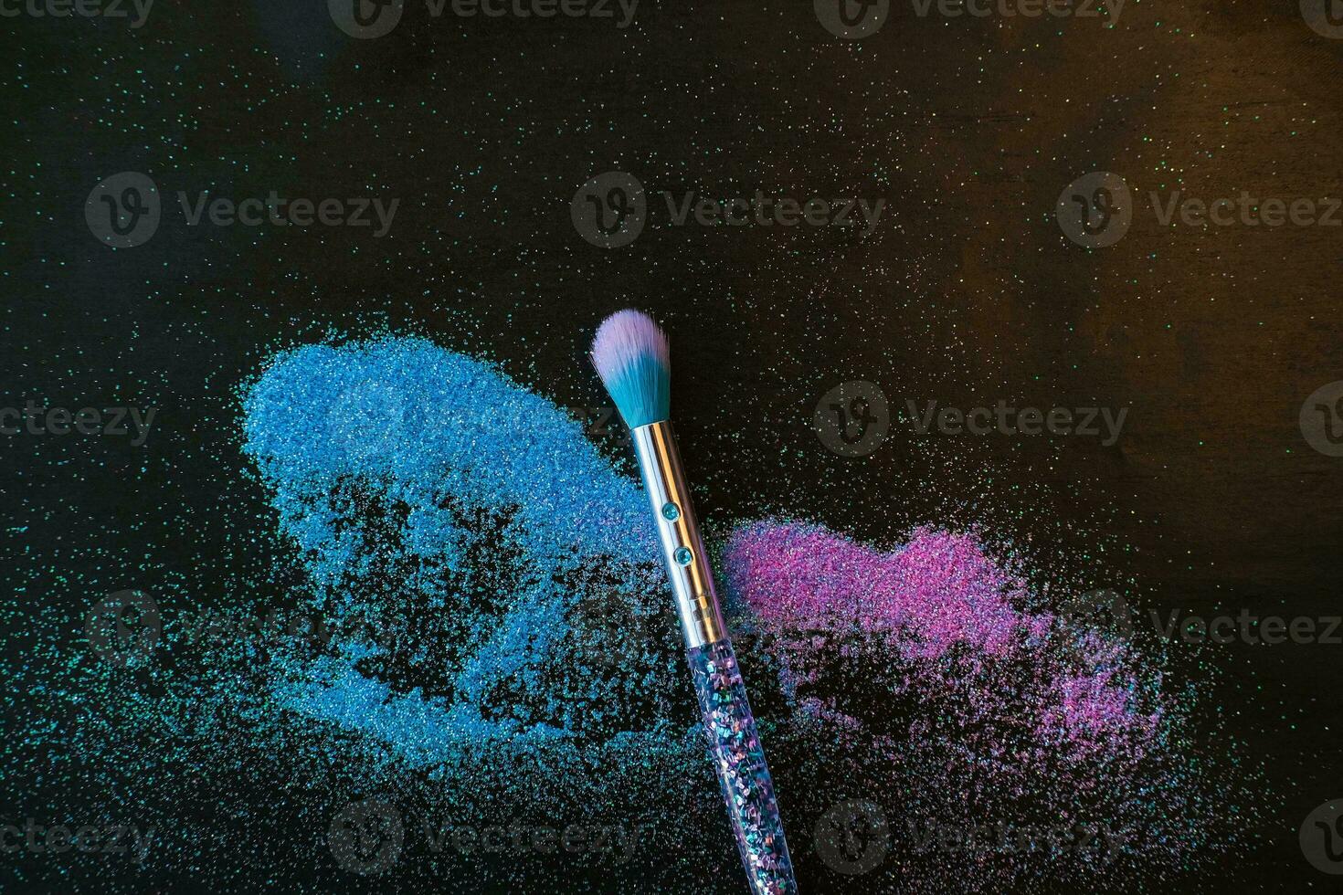 Makeup brush and shiny pink and blue sequins on a black background. Festive magic makeup concept. Template for design, top view Flat Lay Copy space. photo