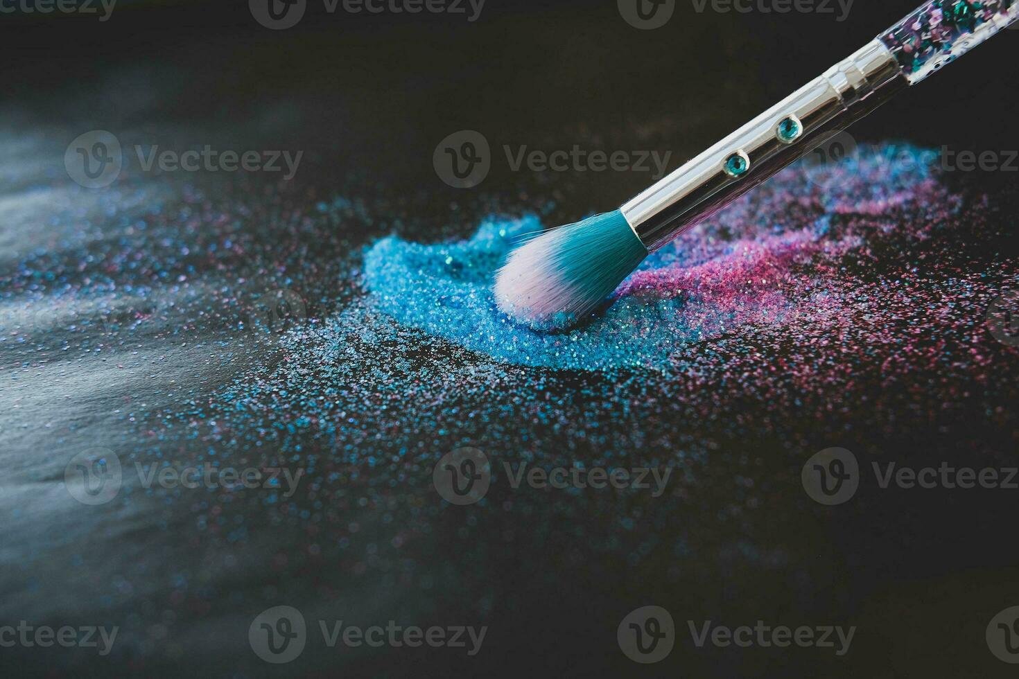 Makeup brush and shiny pink and blue sequins on a black background. Festive magic makeup concept. Template for design. Copy space. photo
