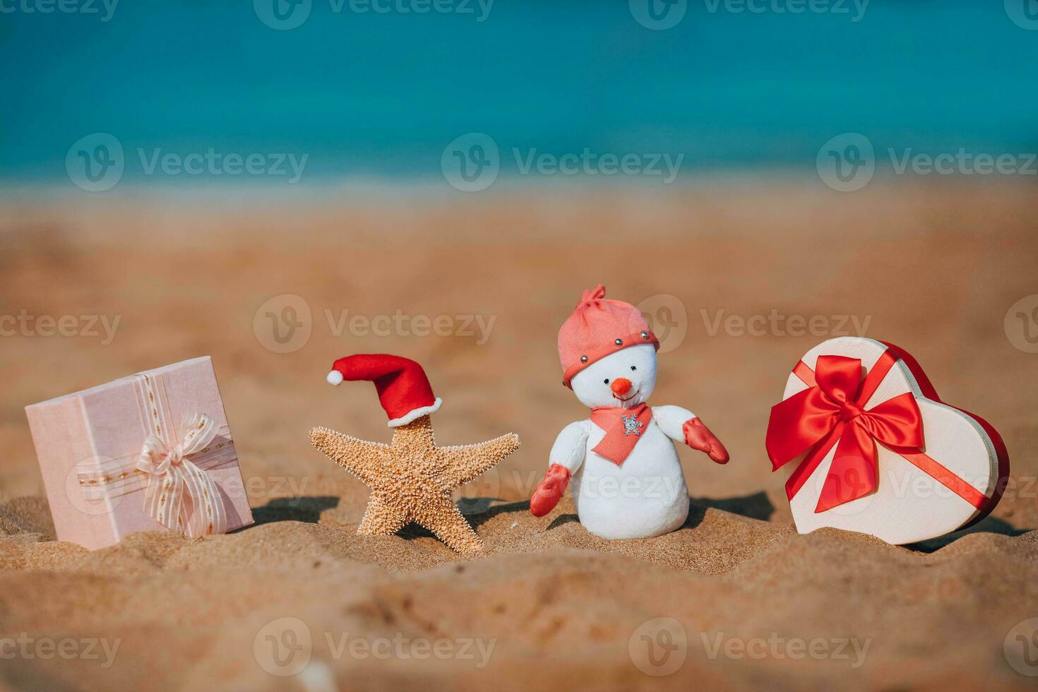 regalo cajas, un estrella de mar en un Papa Noel sombrero y un hecho a mano monigote de nieve en el playa. fiesta Navidad concepto. foto