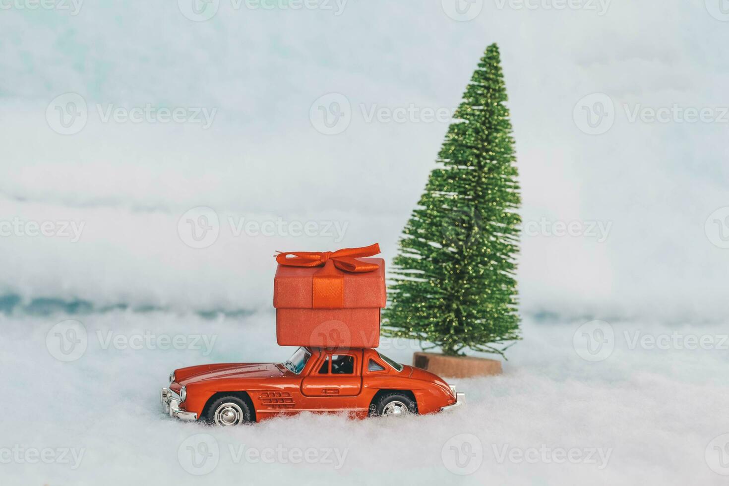 Krasnodar, Russia - December 10, 2019 Red toy car with a gift on the roof, rides in the snow. Delivery of gifts. Copy space. Christmas . New year. photo
