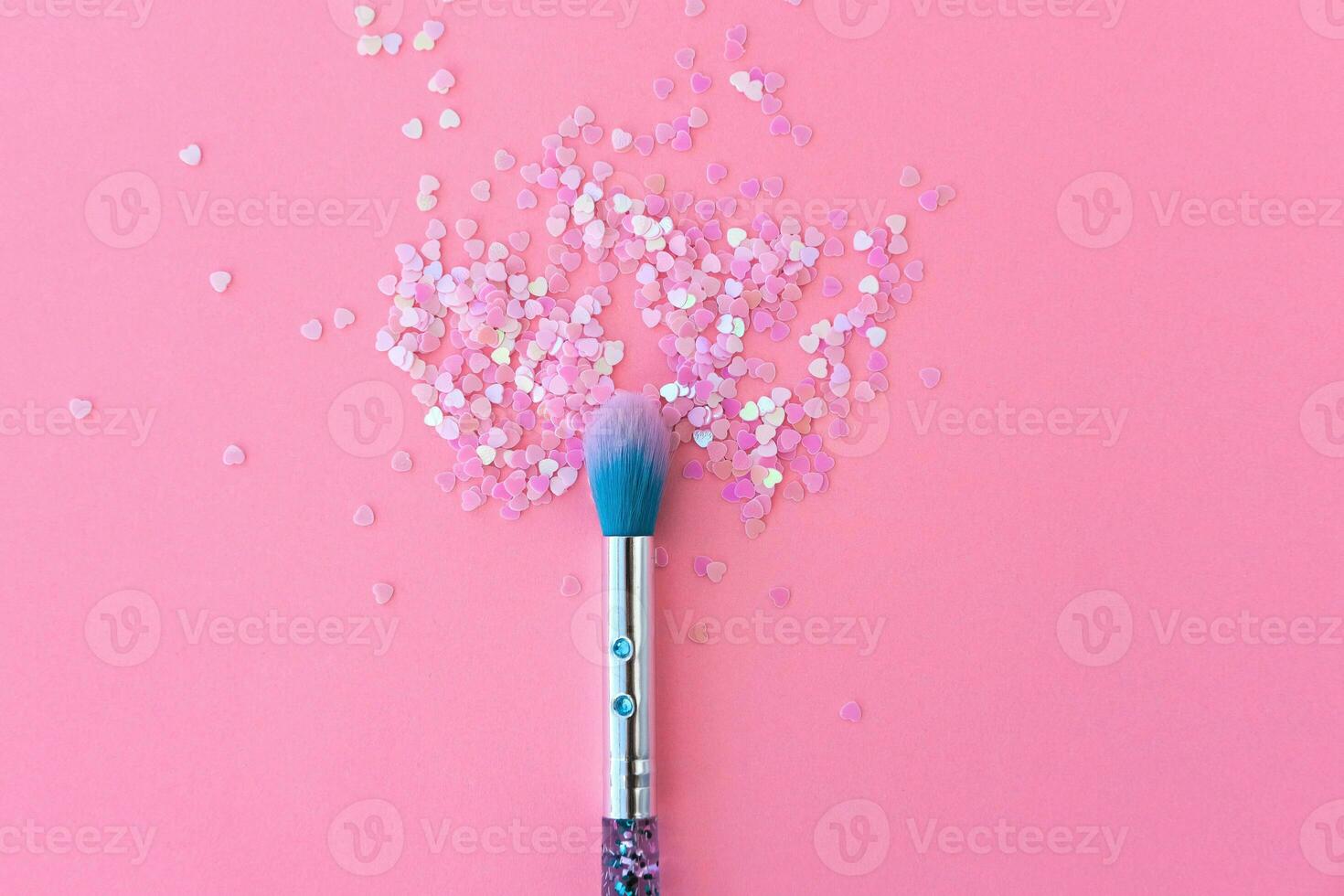 Makeup brush and shiny pink sequins on a pink background. Festive magic makeup concept. Template for design, top view Flat Lay Copy space. photo