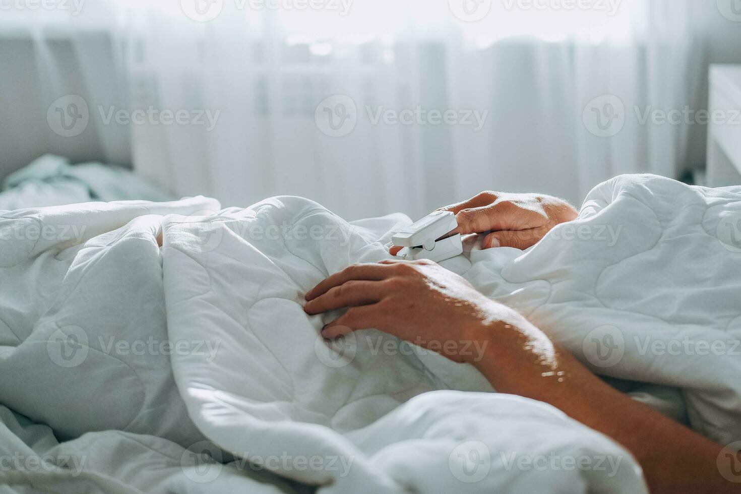 The man lies in bed and measure the oxygen saturation with a pulse oximeter. Asthma treatment. The sick male lies in bed. Bedroom or hospital room . photo