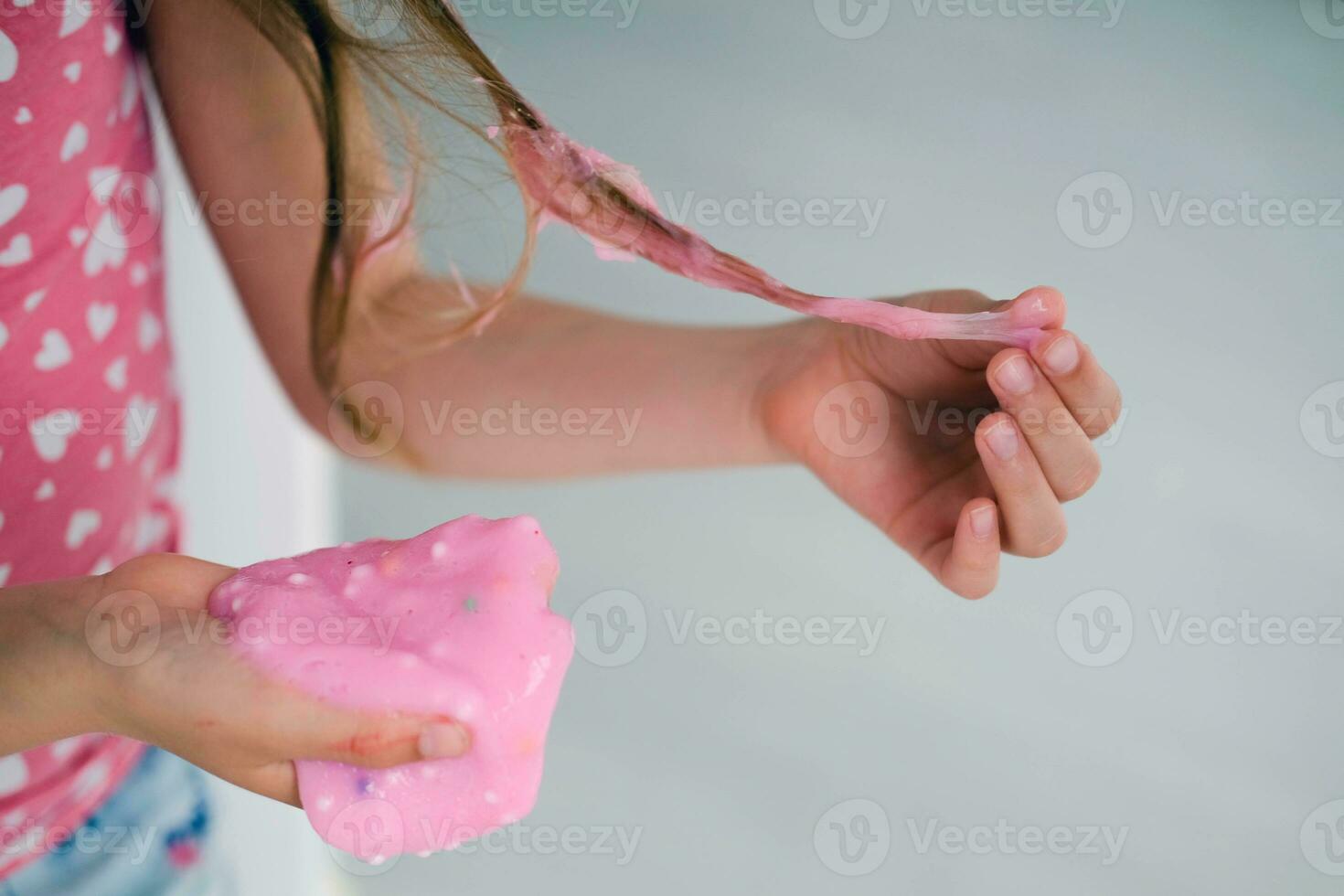 A little girl stained her hair with slime. Child hair tangled in pink slime. photo