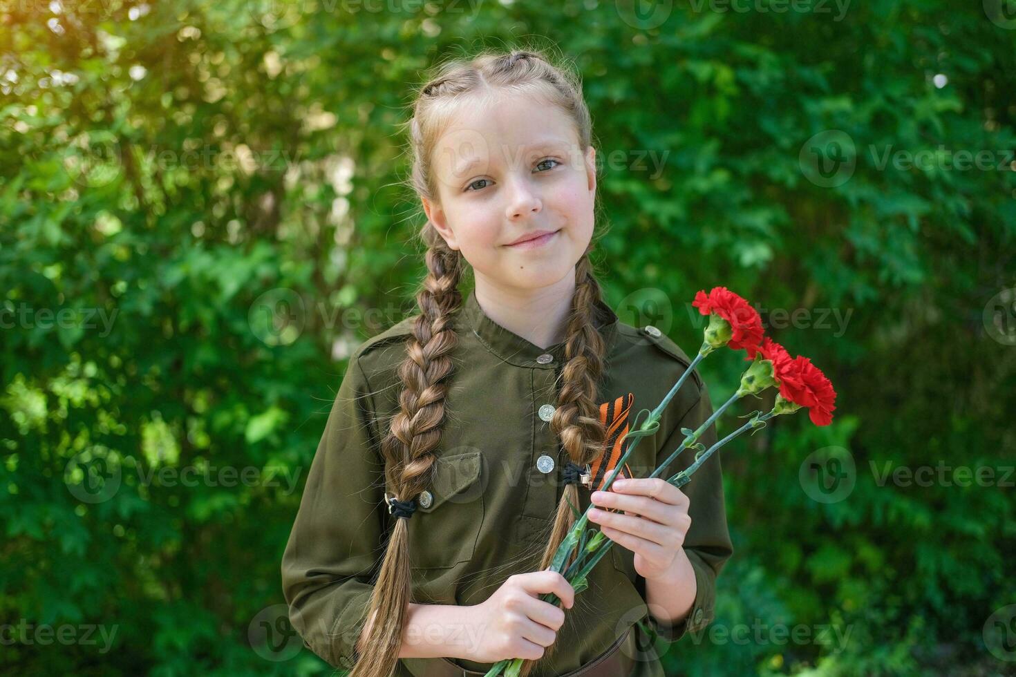 A girl in a special uniform with a St. George ribbon holds three carnations in her hands. Holiday Victory Day May 9th. photo