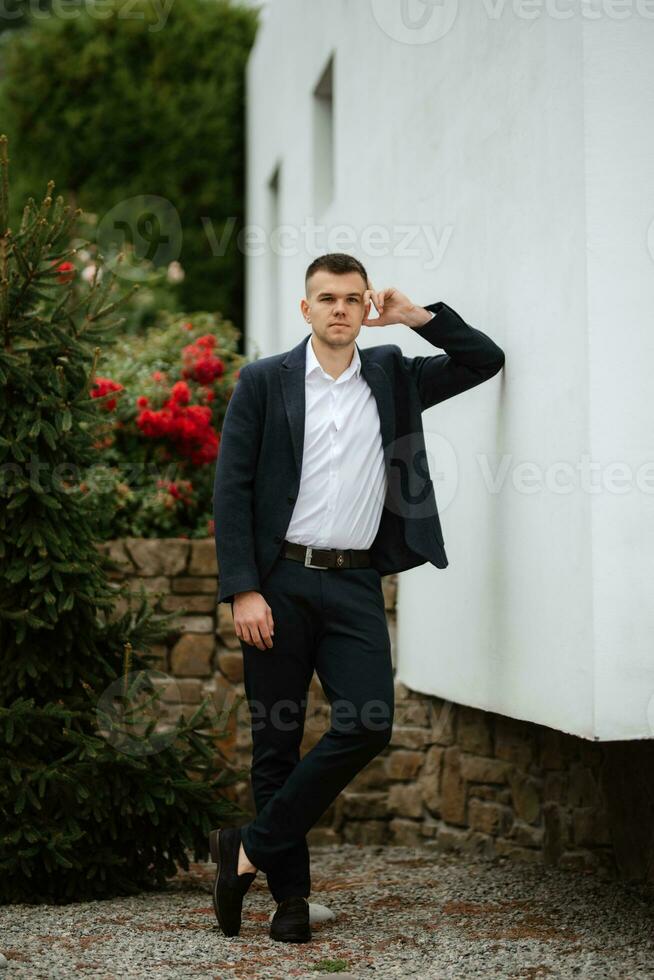 portrait of a young guy groom in a dark wool suit photo