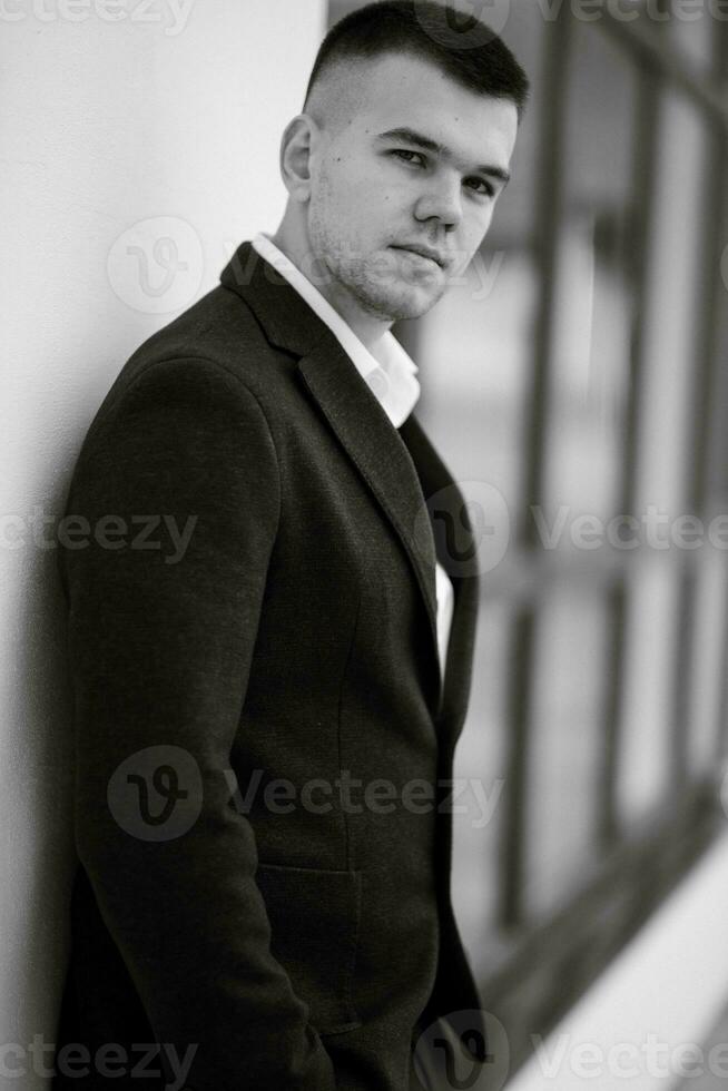 portrait of a young guy groom in a dark wool suit photo