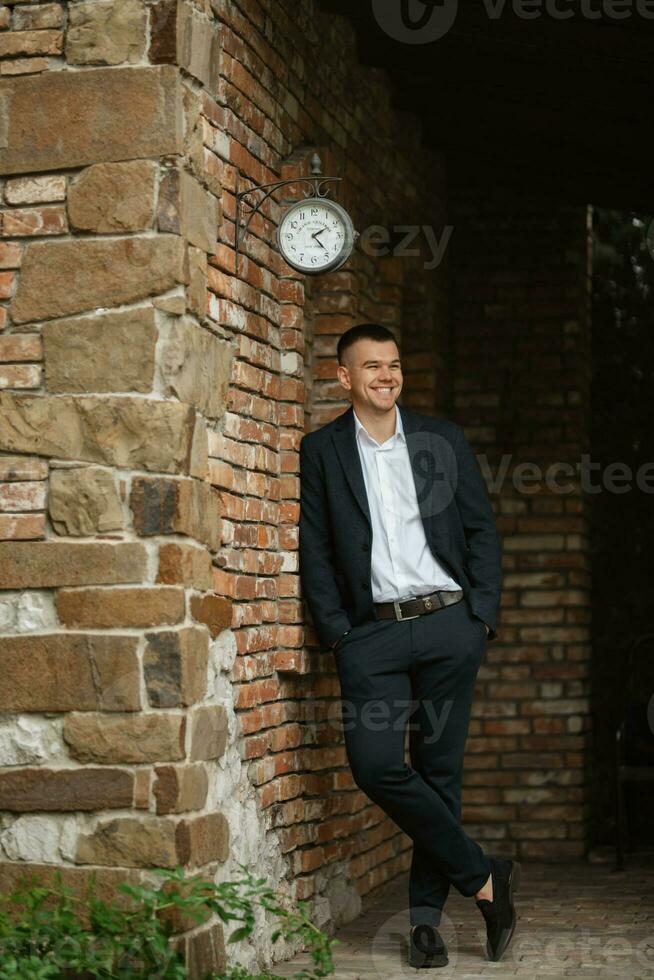 portrait of a young guy groom in a dark wool suit photo