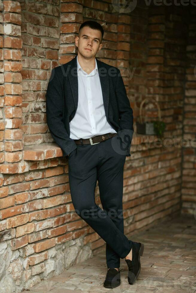 portrait of a young guy groom in a dark wool suit photo