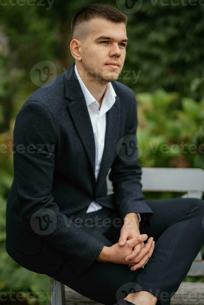 portrait of a young guy groom in a dark wool suit photo