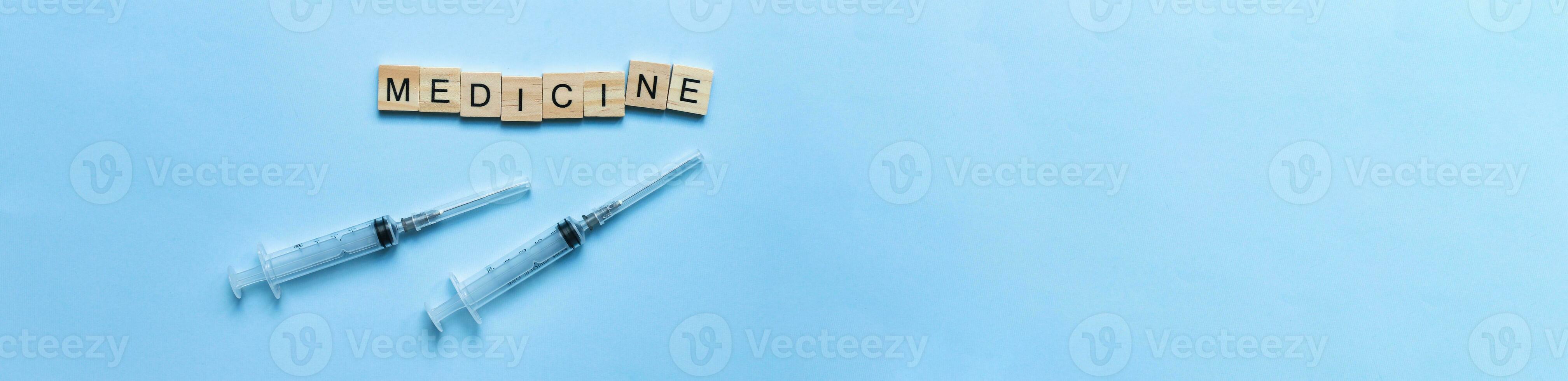 banner Flat lay word medicine laid out from wooden letters. Syringe, ampoule, vaccine. Disease vaccinations photo