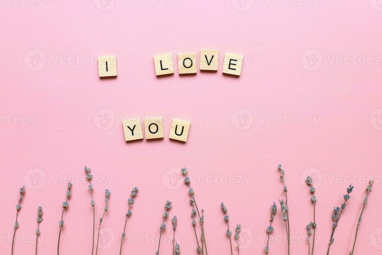 I love you made of wooden letters on a pink background with flowers. mothers day card. Flat lay for mothers day. I love you layout photo