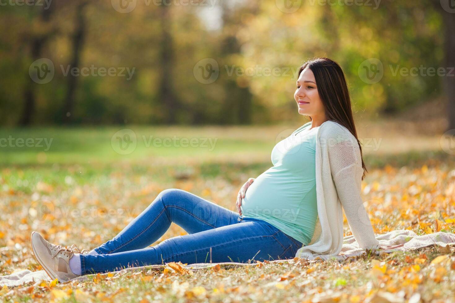 un embarazada mujer gasto hora al aire libre foto