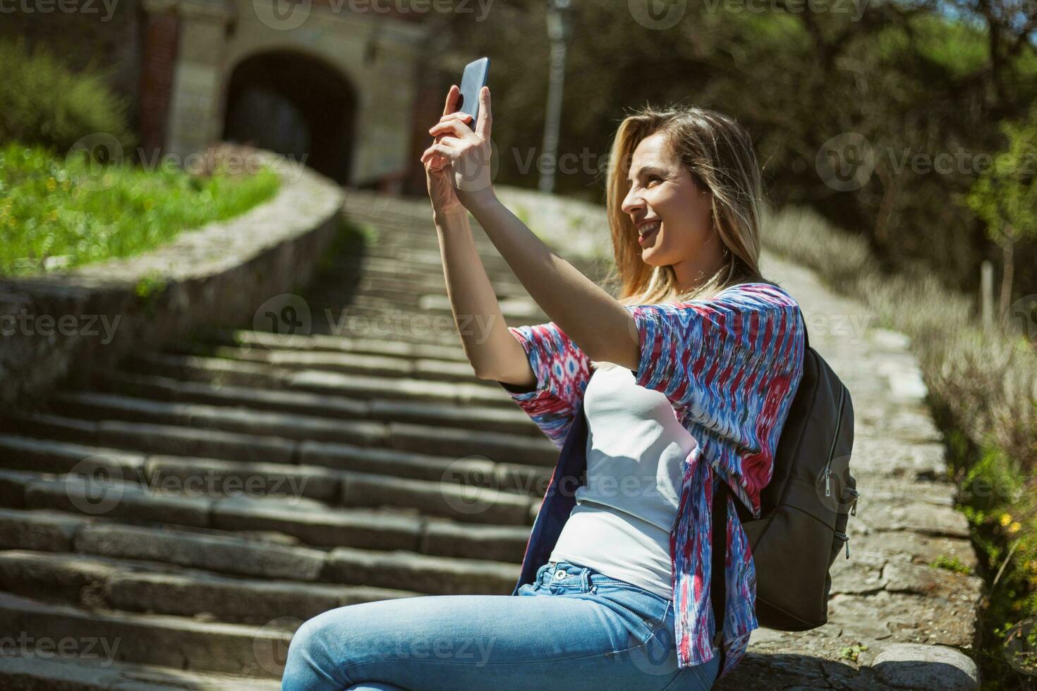 Young tourist woman sitting by the stairs with her phone photo