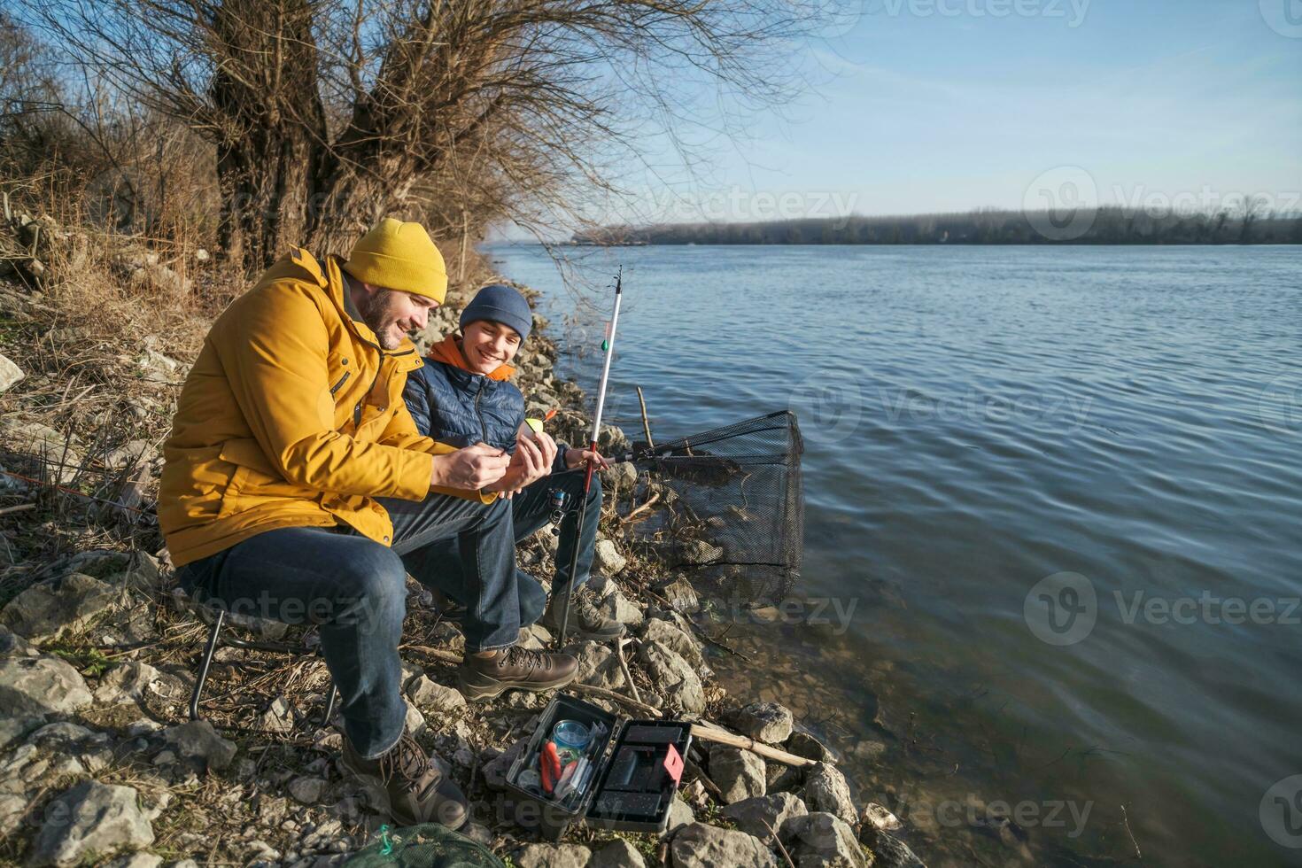 Father and son are fishing on sunny winter day photo