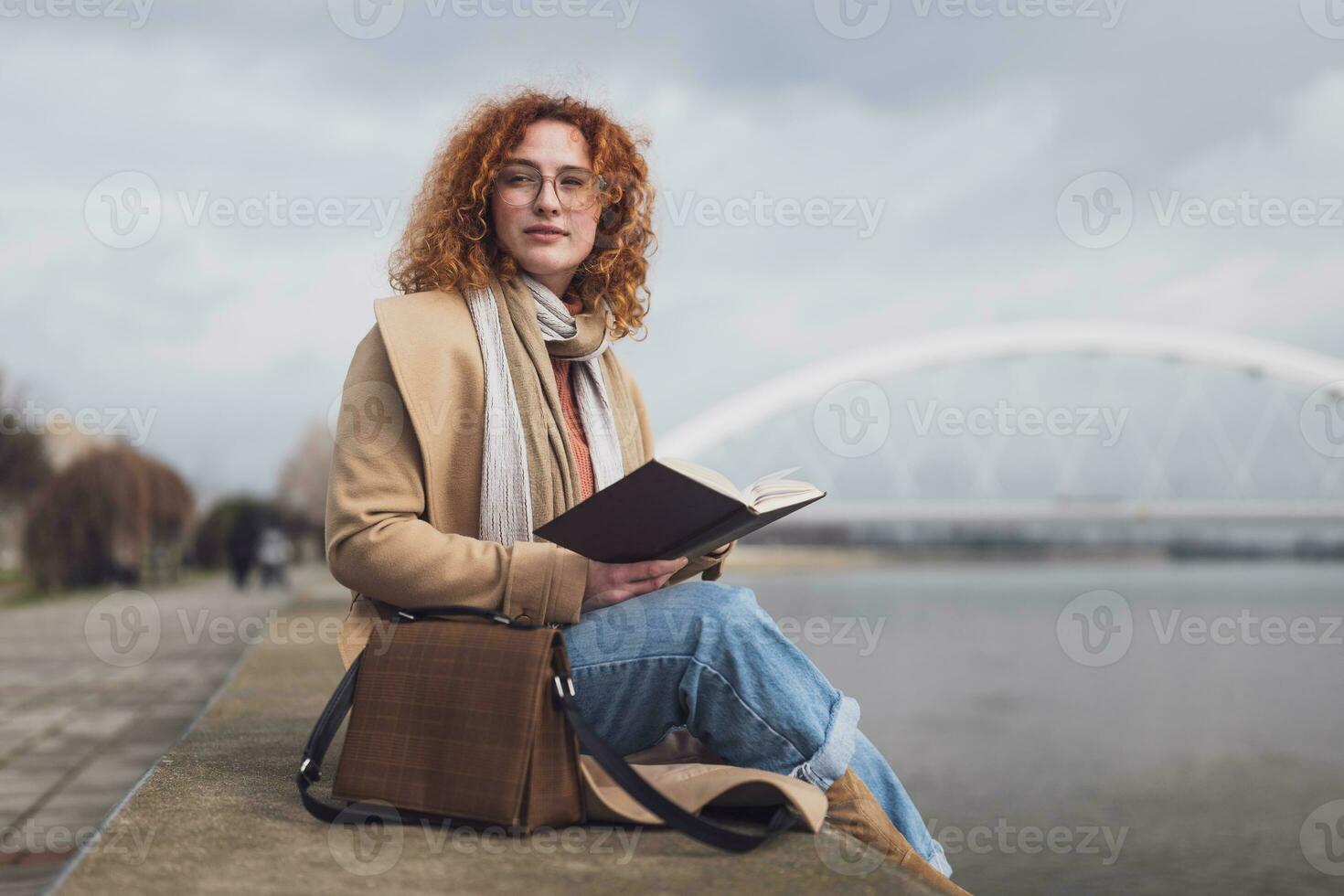 joven mujer con pecas y Rizado jengibre pelo con cuaderno al aire libre foto
