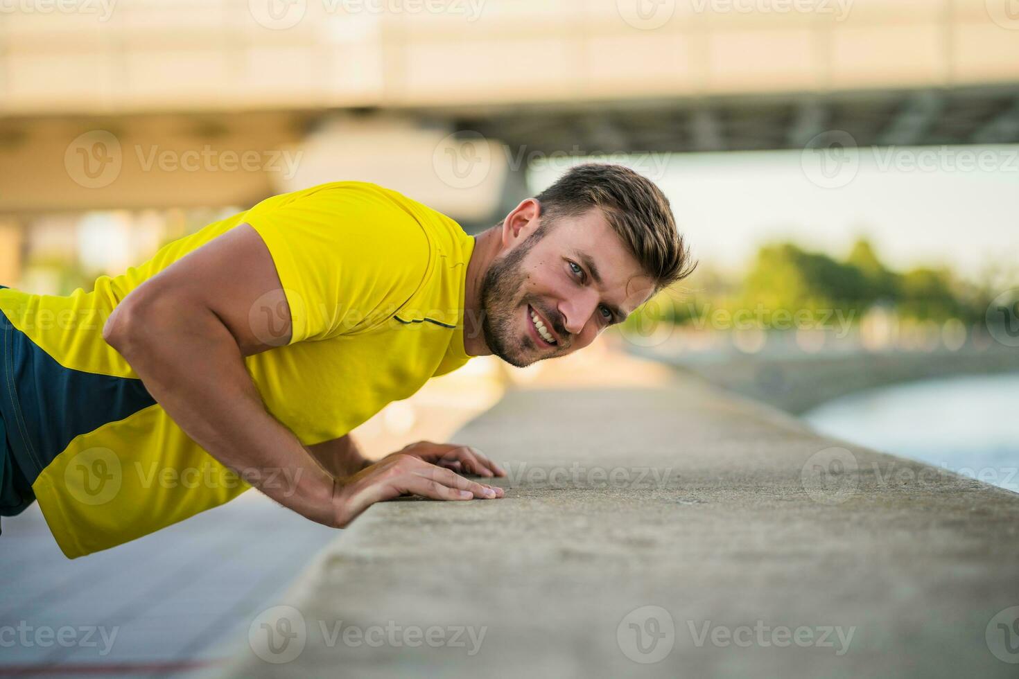 A man in a yellow t-shirt doing physical exercises photo