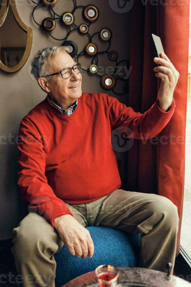 A senior man in a red sweater relaxing photo