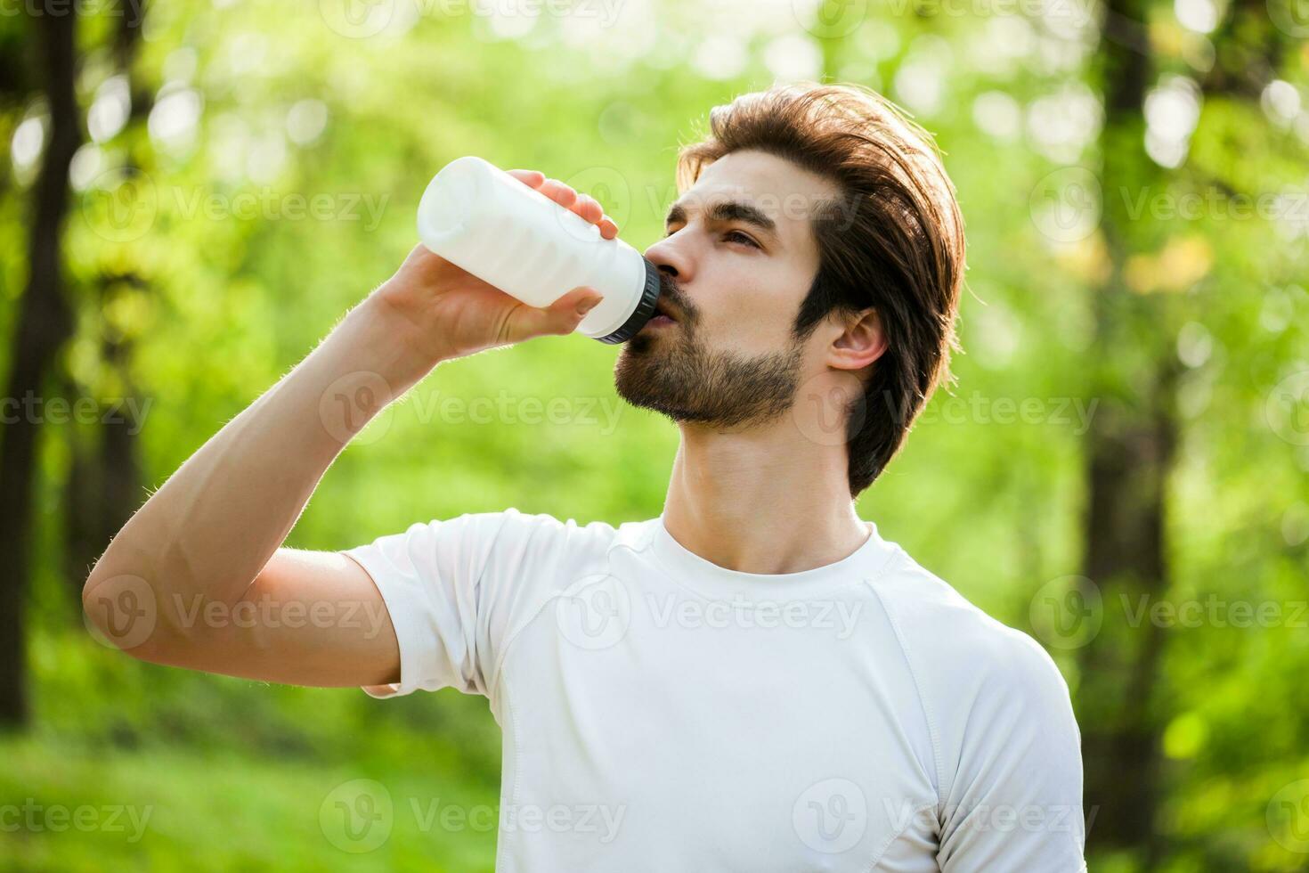 A man drinking water after doing physical exercises photo