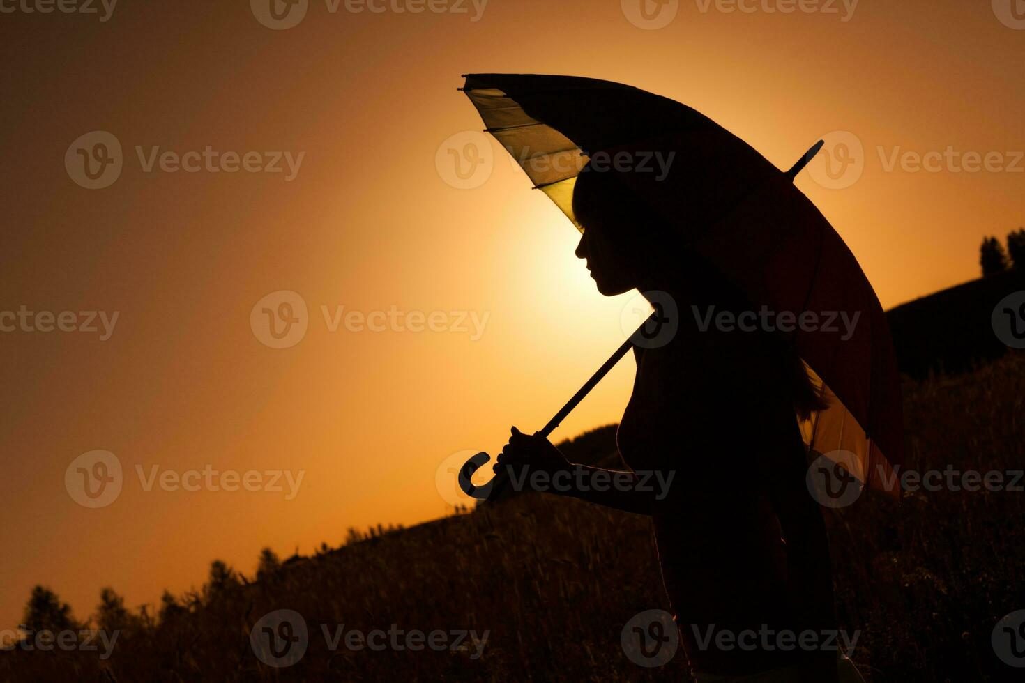 silueta de un mujer con paraguas terminado el puesta de sol foto