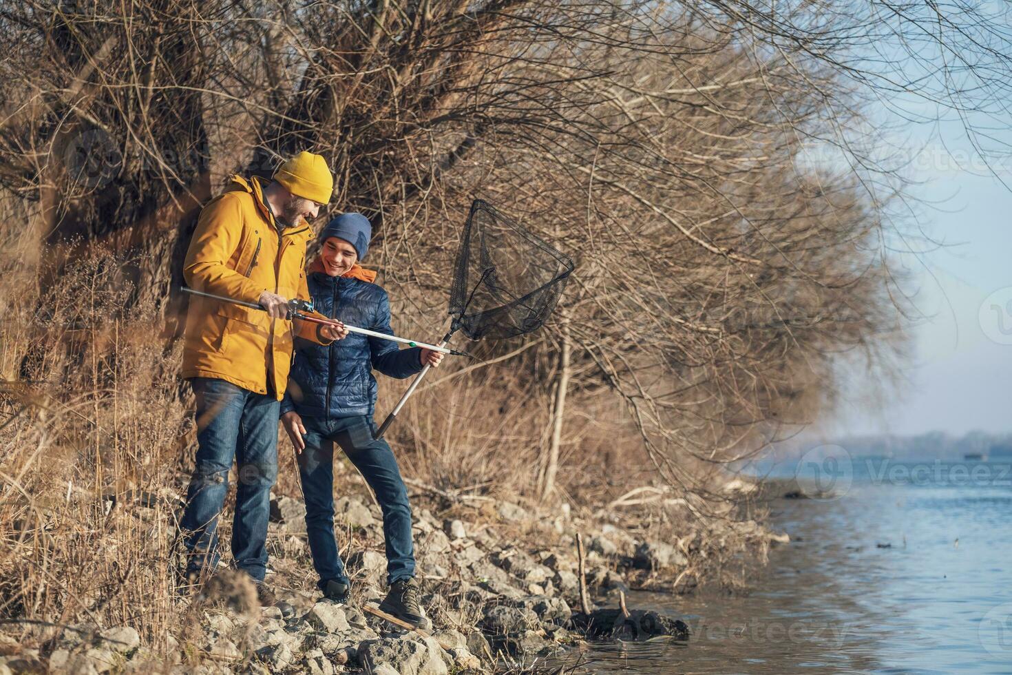 Father and son are fishing on sunny winter day photo