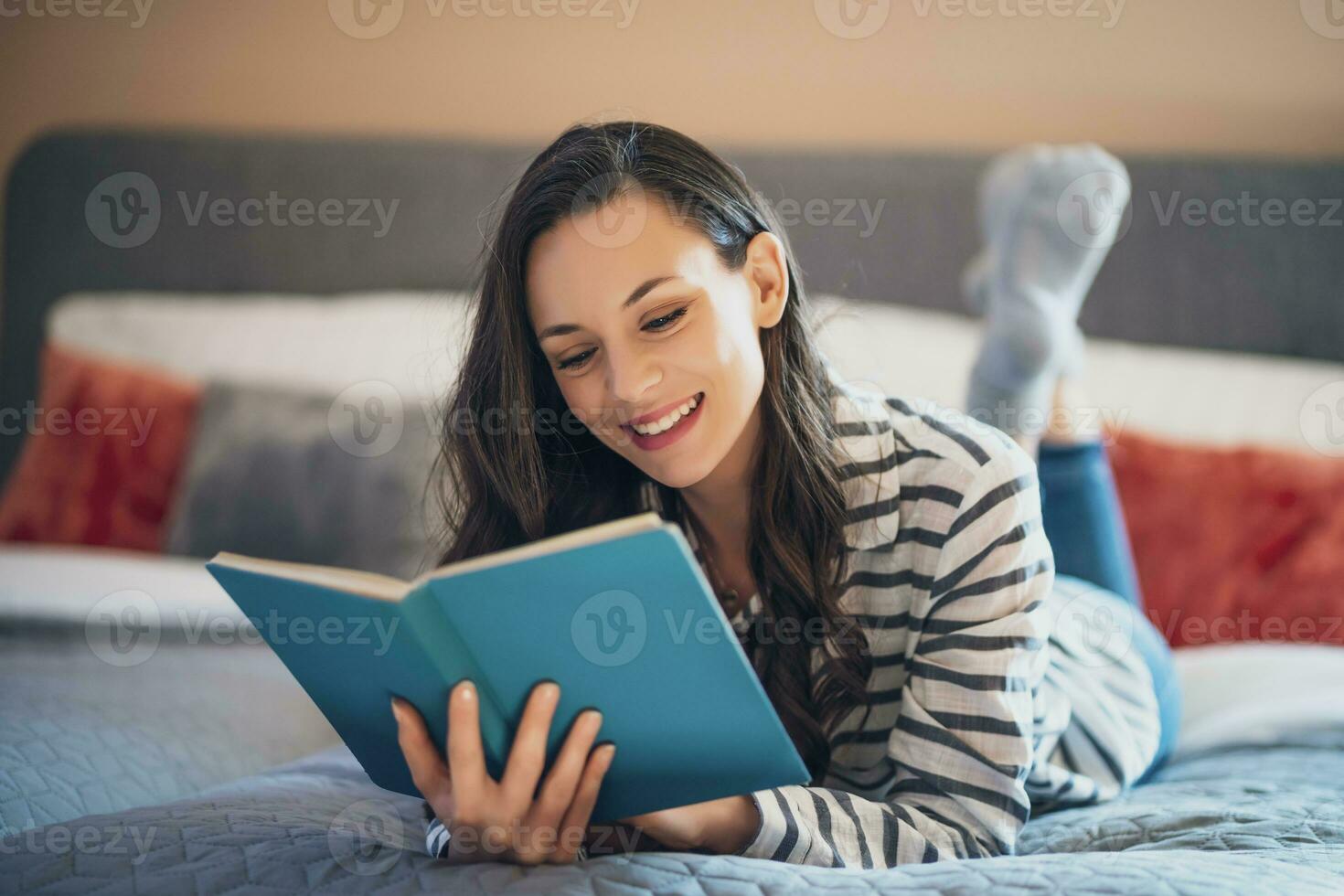 A woman reading a book in her bed photo