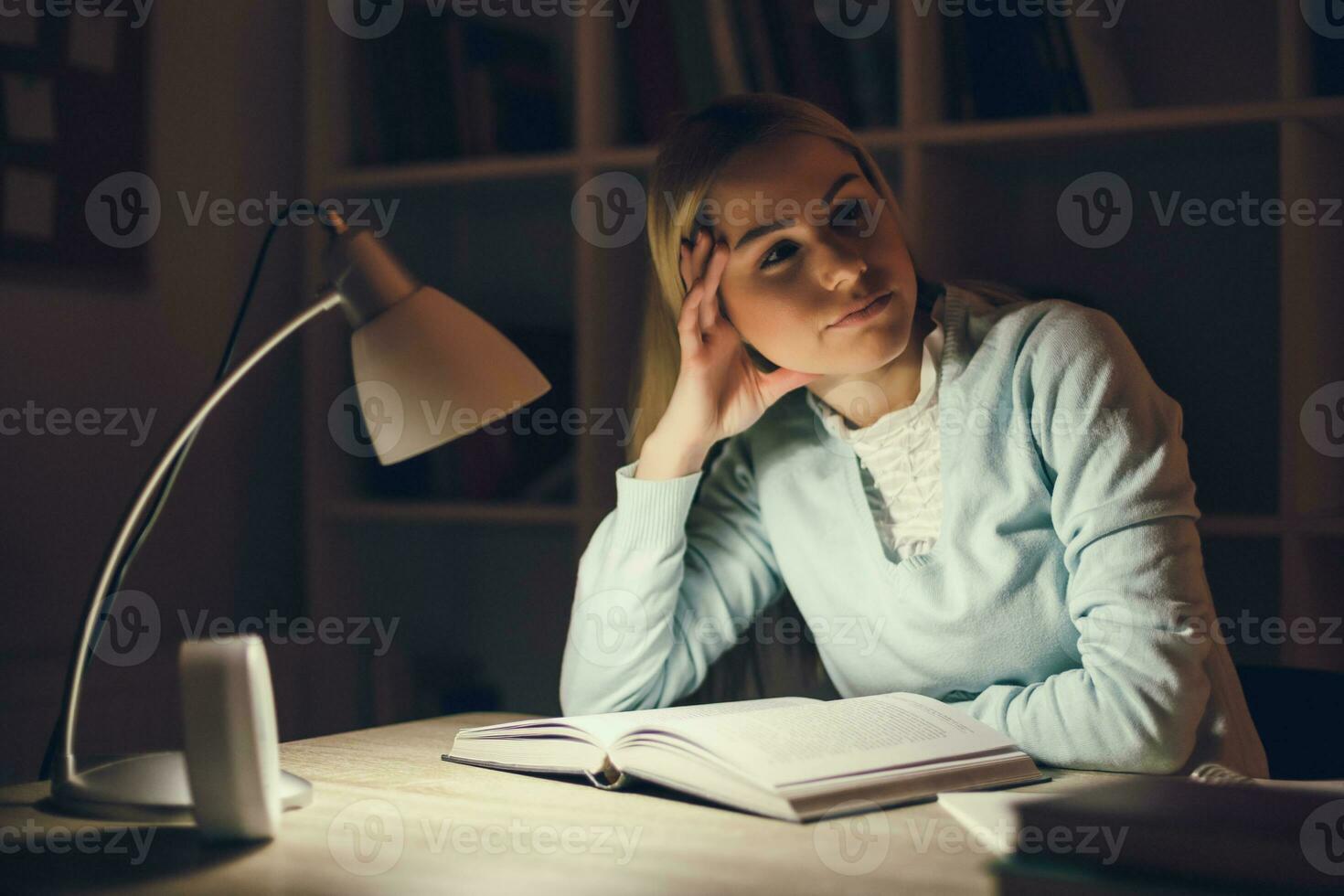 Young blonde woman studying at night photo