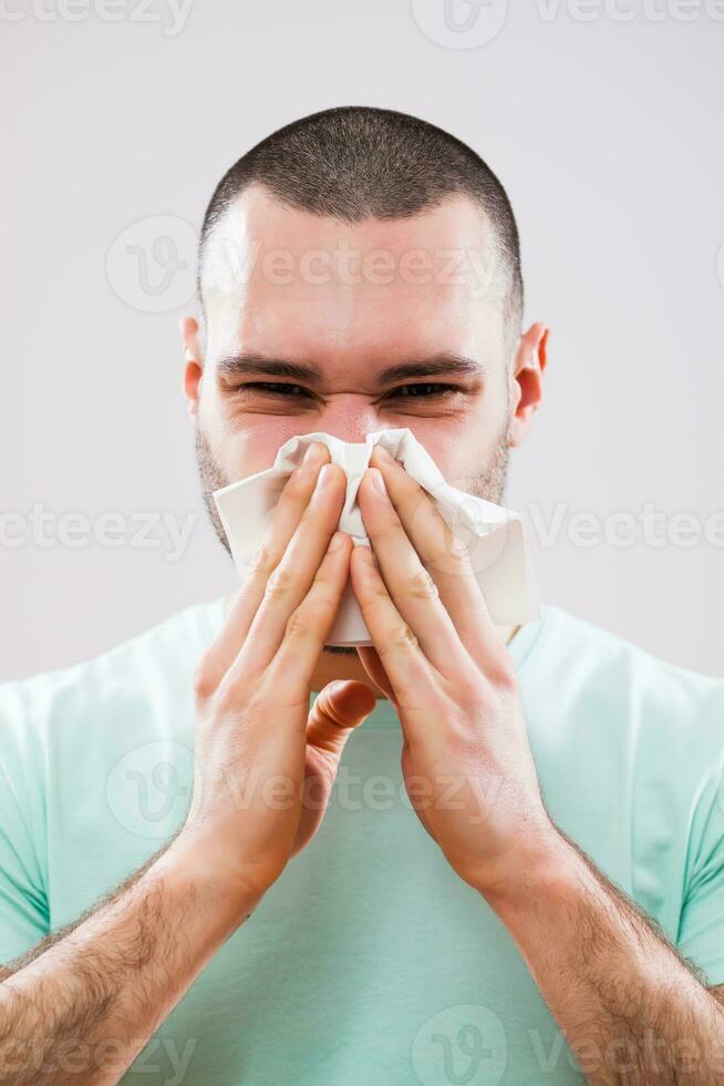 A man with green tshirt blowing his nose photo