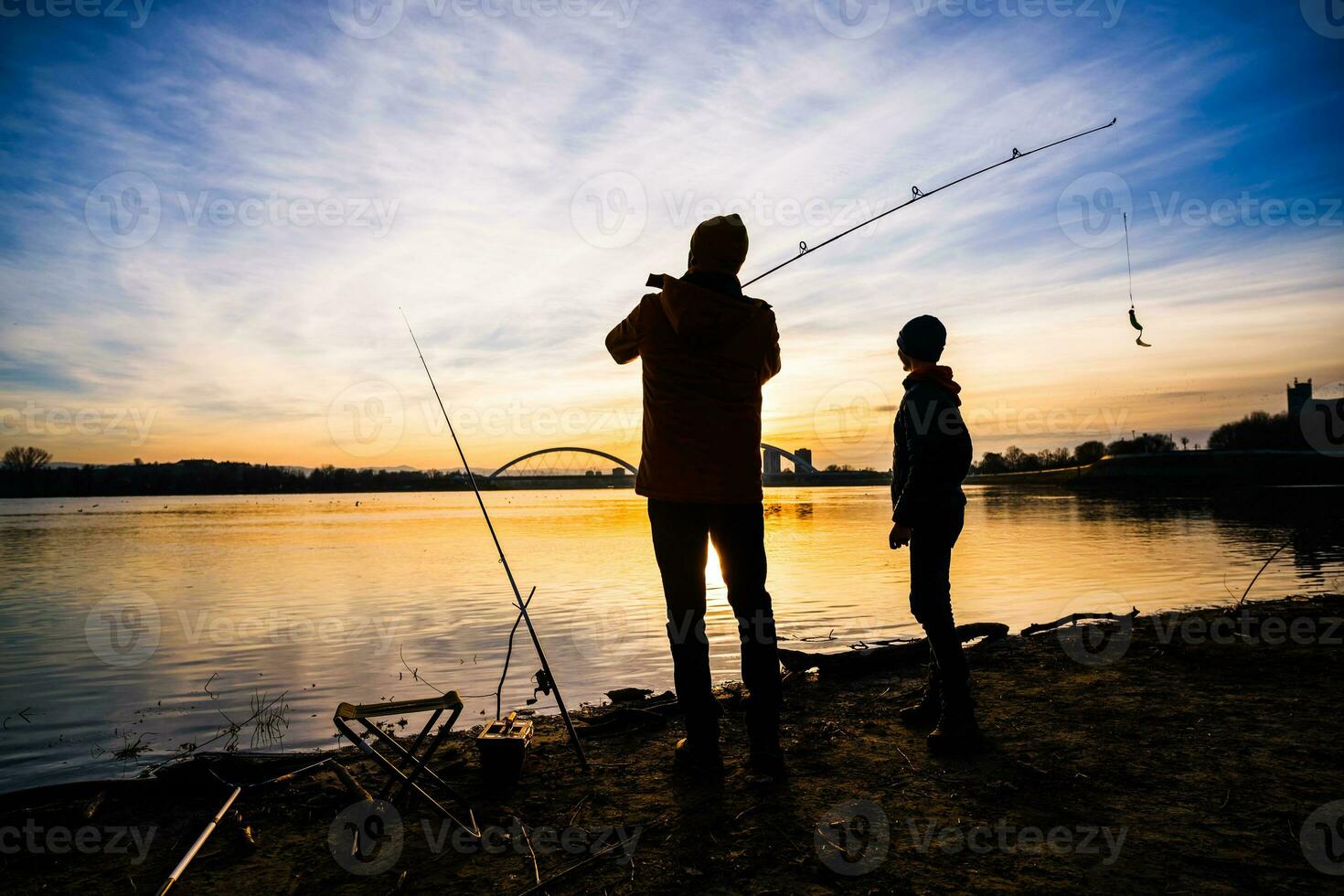 Father and son are fishing on sunny winter day photo