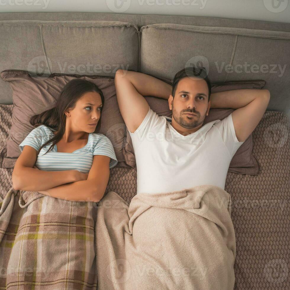 A young couple lying in bed with relationship issues photo