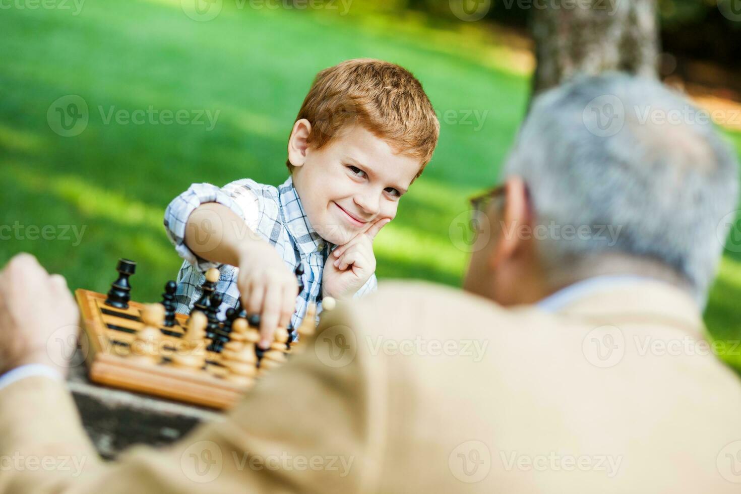 A grandfather and his grandson playing chess photo