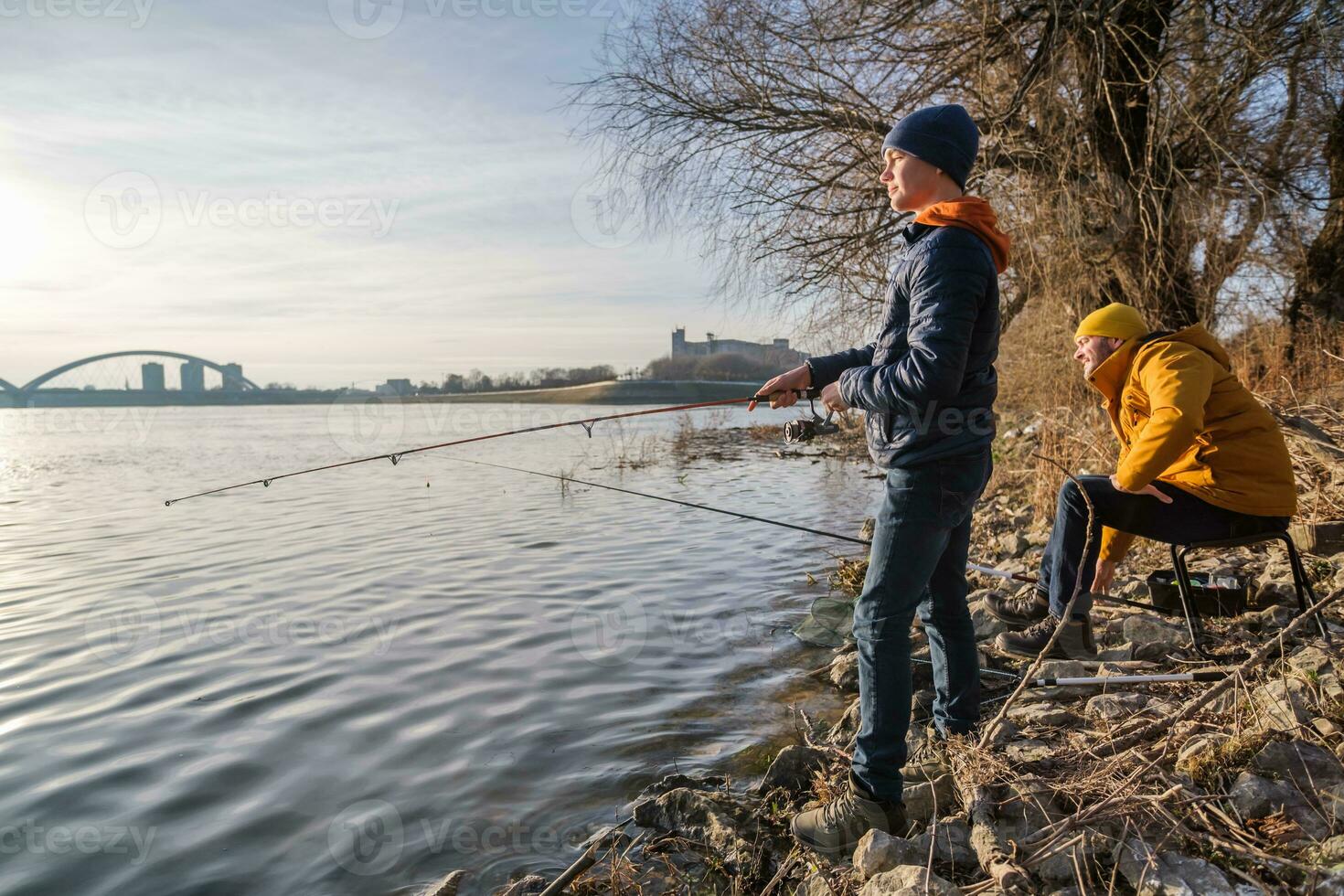 Father and son are fishing on sunny winter day photo